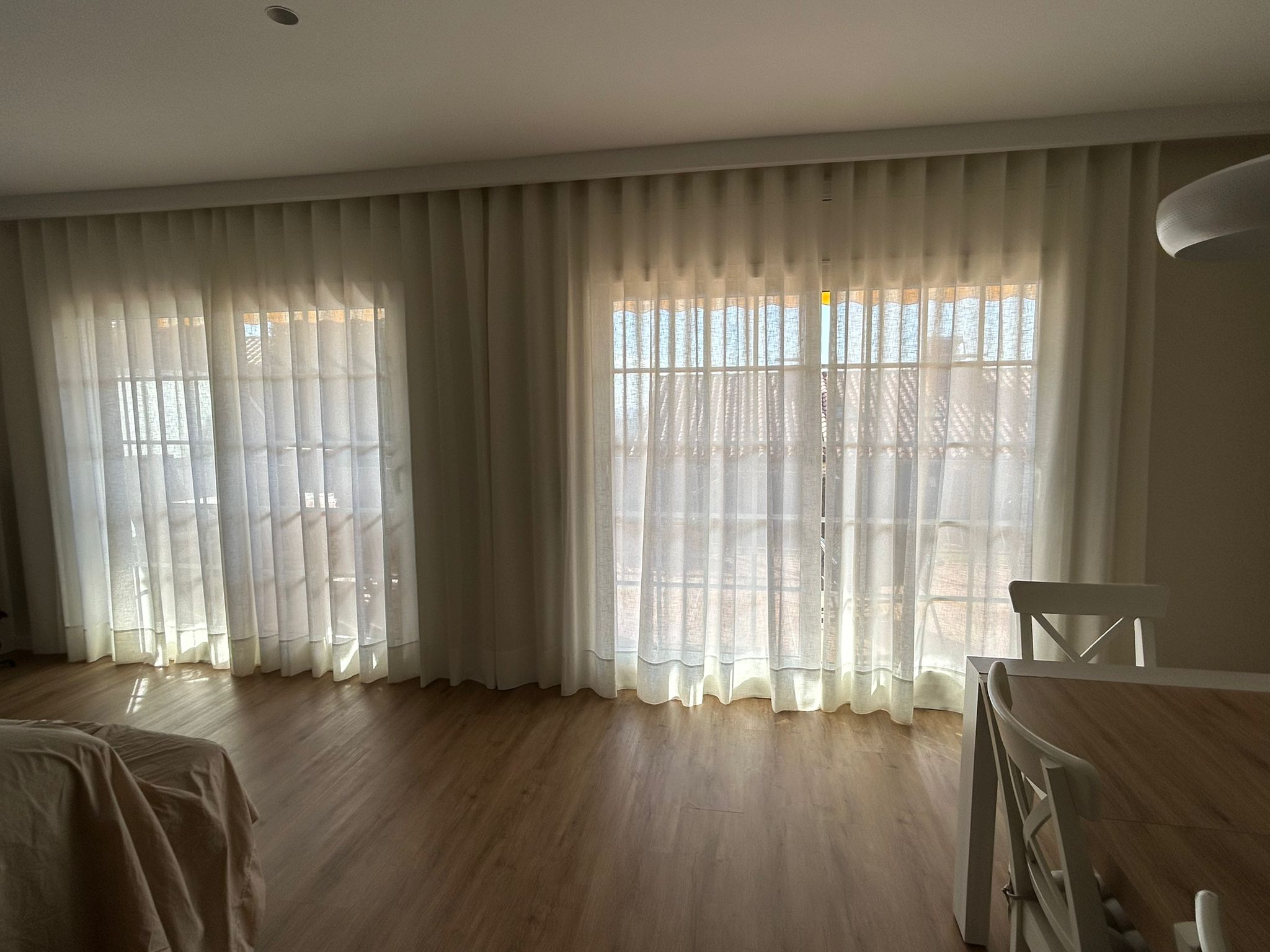 Cortinas tradicionales con confección de onda perfecta instaladas en salón comedor en Teià