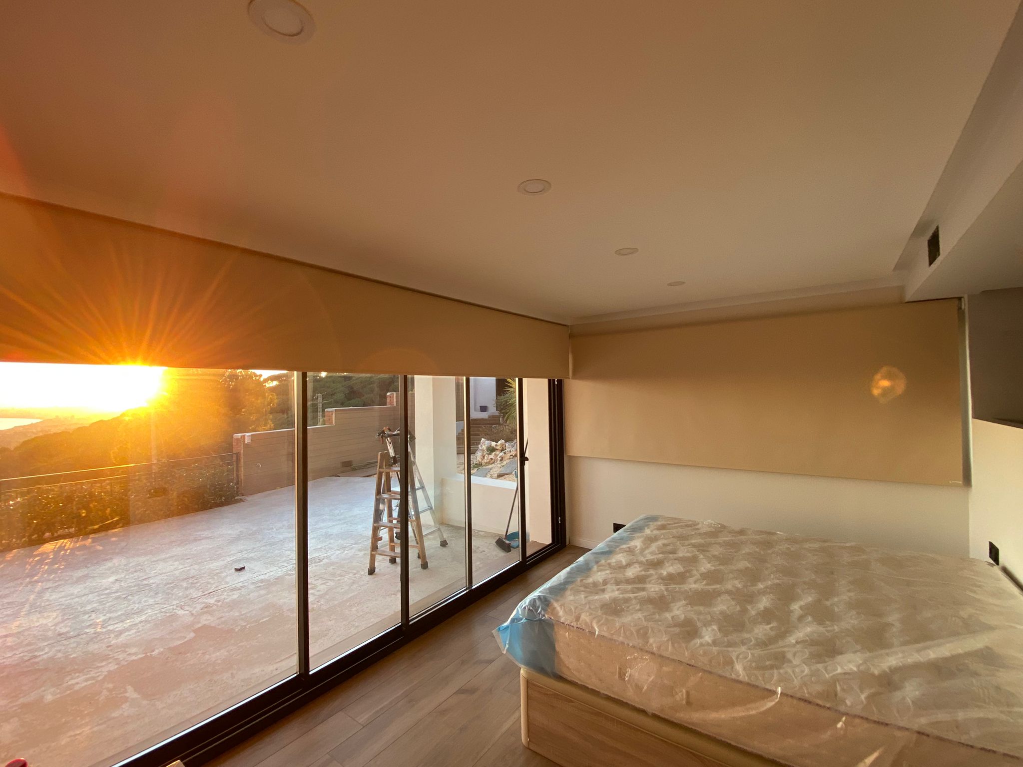 Cortinas opacas enrollables motorizadas instaladas en dormitorio de casa unifamiliar