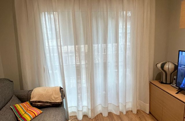 Instalación de cortina tradicional con riel básico, referencia Bavay tejido 50% Poliéster 50% Lino y color 02 Nacar, en vivienda de Barcelona 