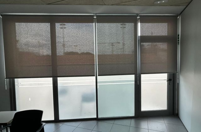 Instalación de cortinas enrollables con tejido técnico screen y accionamiento a manivela extraíble, referencia 420P abertura del 1% y color Pearl Grey, en oficinas de Barcelona