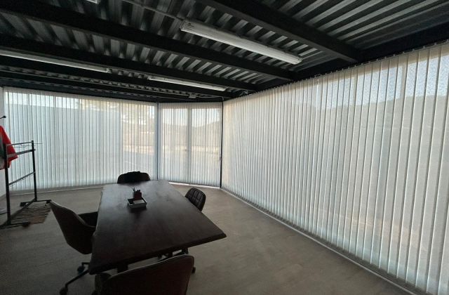 Cortinas de lamas verticales con tejido técnico screen instaladas en ventanales de despacho