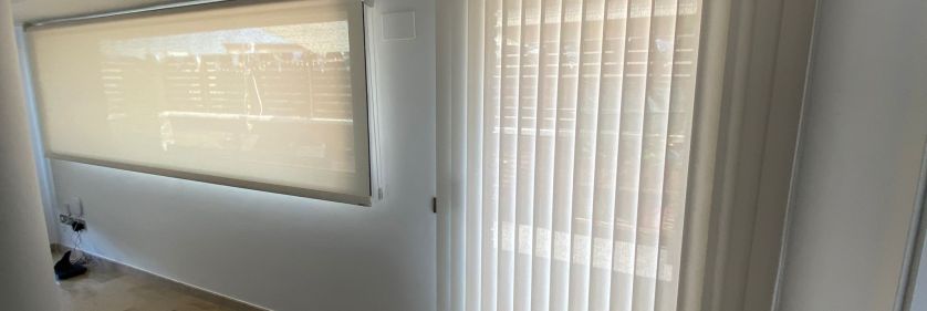 Estor enrollable y cortina vertical de lamas, instaladas en ventanales en Manresa