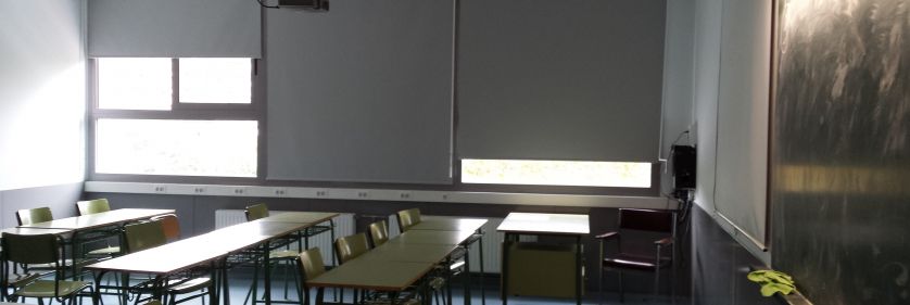 Cortinas enrollables opacas grises en aula con proyector