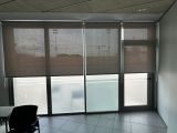 Instalación de cortinas enrollables con tejido técnico screen y accionamiento a manivela extraíble, referencia 420P abertura del 1% y color Pearl Grey, en oficinas de Barcelona