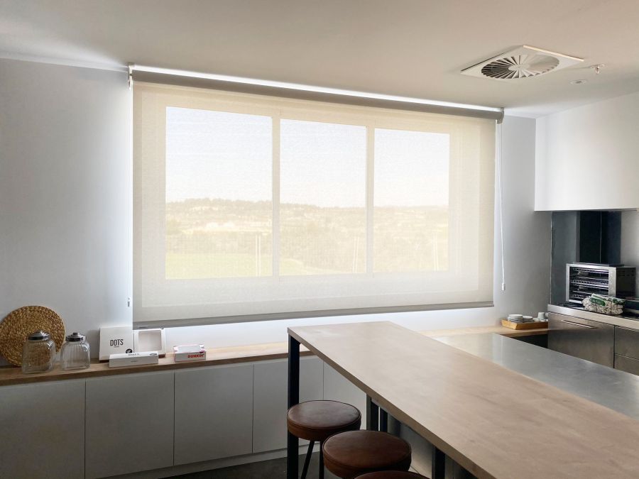 Cortina enrollable de color lino, con tejido técnico screen, para ventana de comedor en una oficina de Tarragona