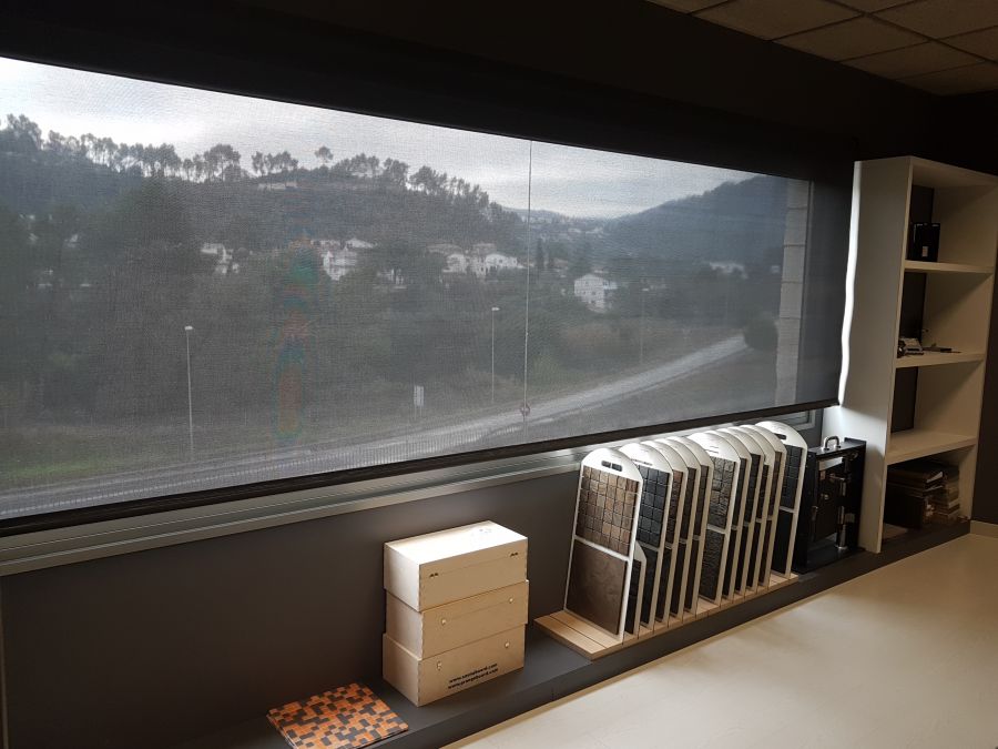 Cortina enrollable de color ebony, con tejido técnico screen, instalada en ventanal de almacén de construcción en Cervelló
