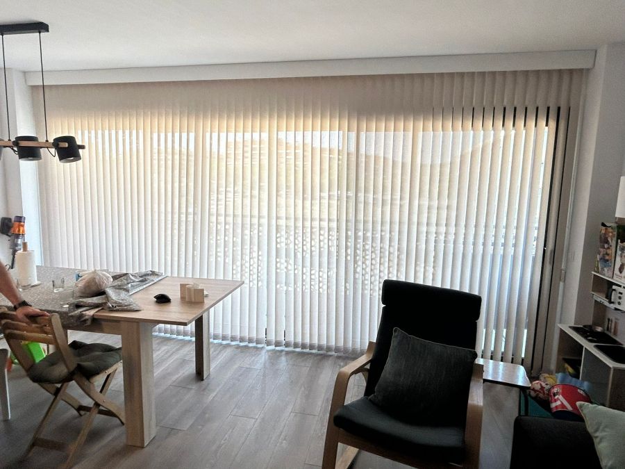 Cortinas de lamas verticales con tejido técnico screen instaladas en comedor de vivienda