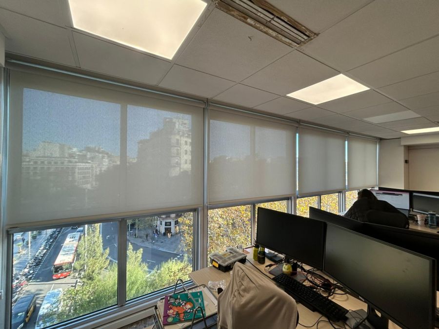 Cortinas enrollables con tejido técnico screen de color gris perla y con accionamiento a cadena, instaladas en oficina en Barcelona
