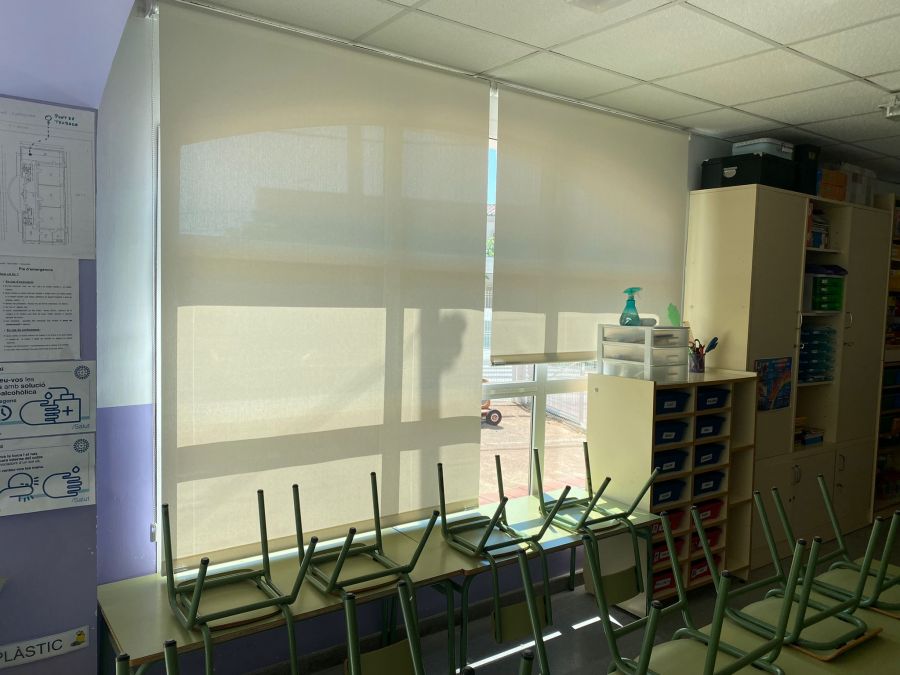 Cortinas enrollables de color blanco, con tejido técnico screen, instaladas en las ventanas de una aula de colegio en Lleida