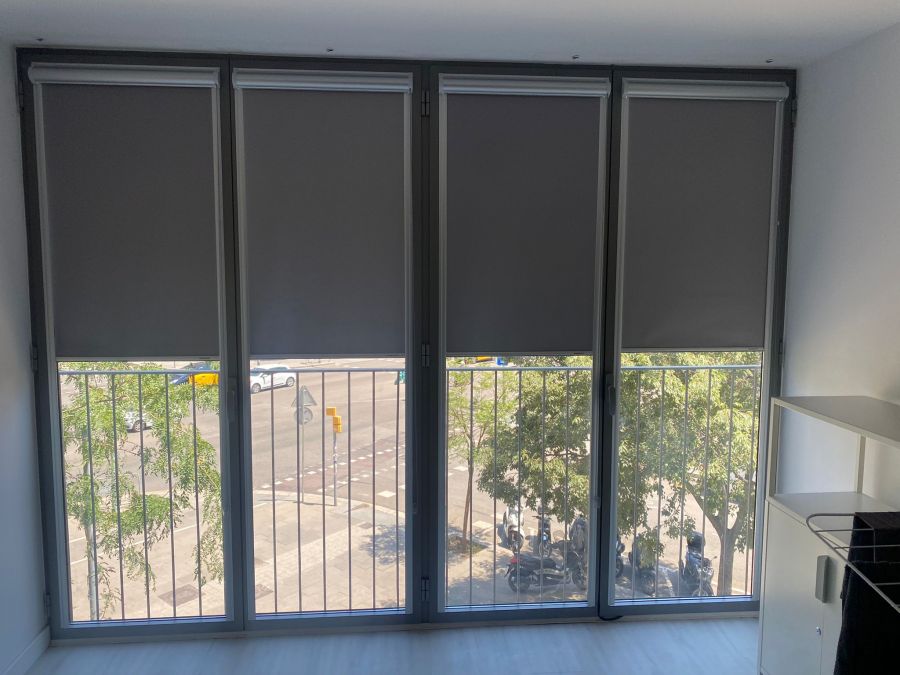 Cortinas enrollables sistema fit con guía plana, con tejidos opacos instaladas en ventanales de oficina en Barcelona, componentes en gris metalizado Cortinas enrollables sistema fit con guía plana, con tejidos opacos instaladas en ventanales de oficina en Barcelona