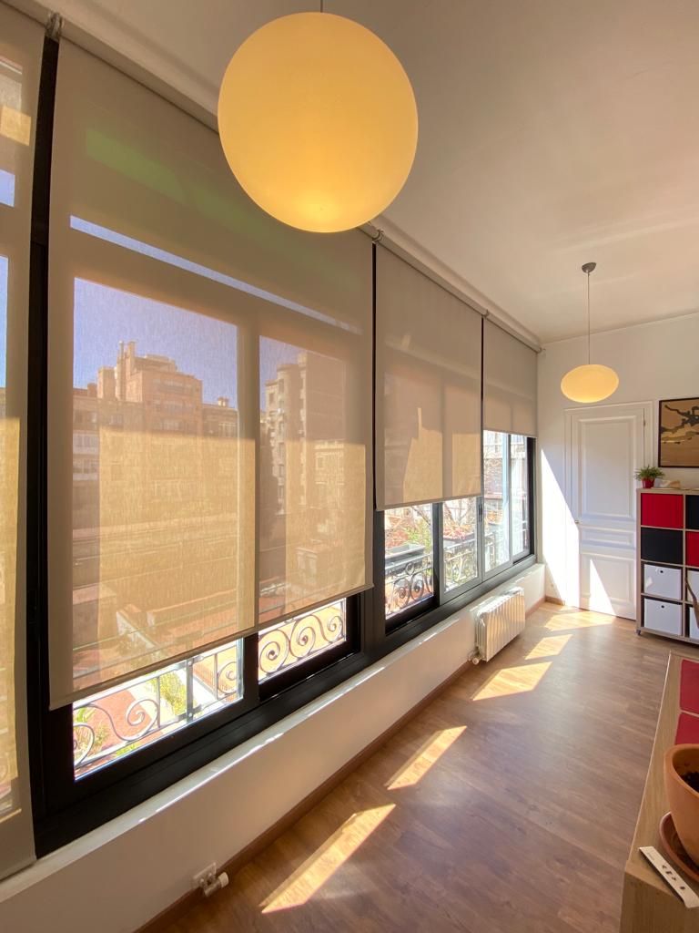 Estores enrollables blancos instalados en cristaleras de salón de vivienda particular