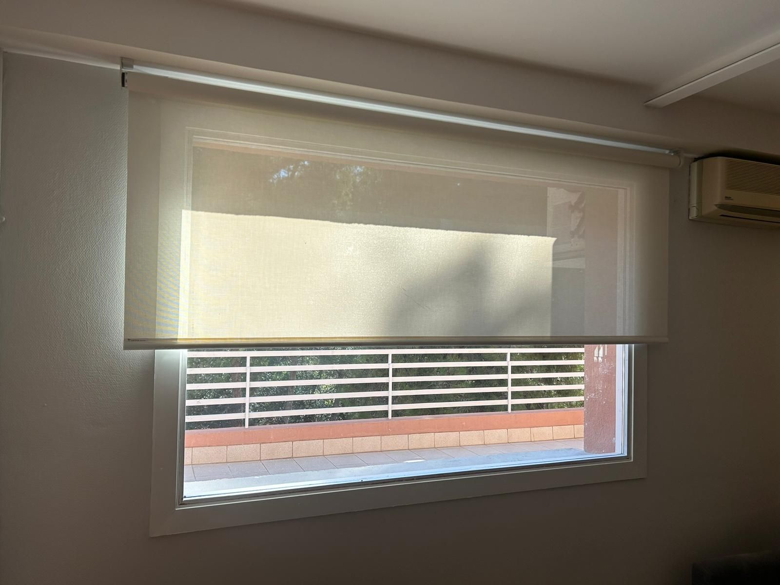 Instalación de cortina enrollable con tejido técnico screen y motor batería, referencia 380P abertura del 5% y color White, en vivienda de Barcelona