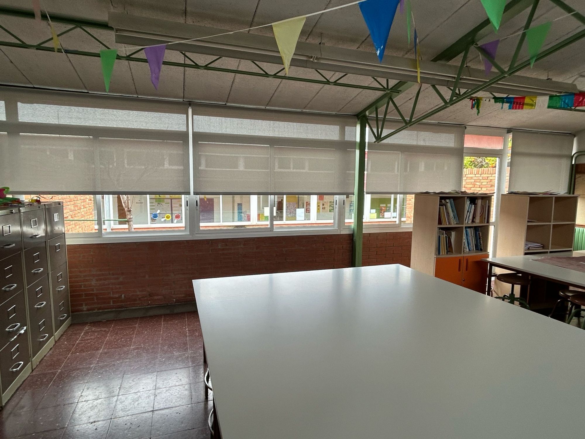 Instalación de cortinas enrollables con tejido técnico screen, referencia PS351 abertura del 1% y color blanco perla, en escuela de Sant Boi de Llobregat